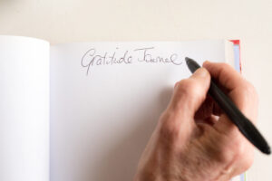 someone writing with a pen in a gratitude journal