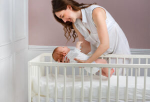 mother lowering an infant into their crib