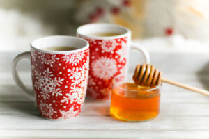 cups of tea sitting next to a jar of honey